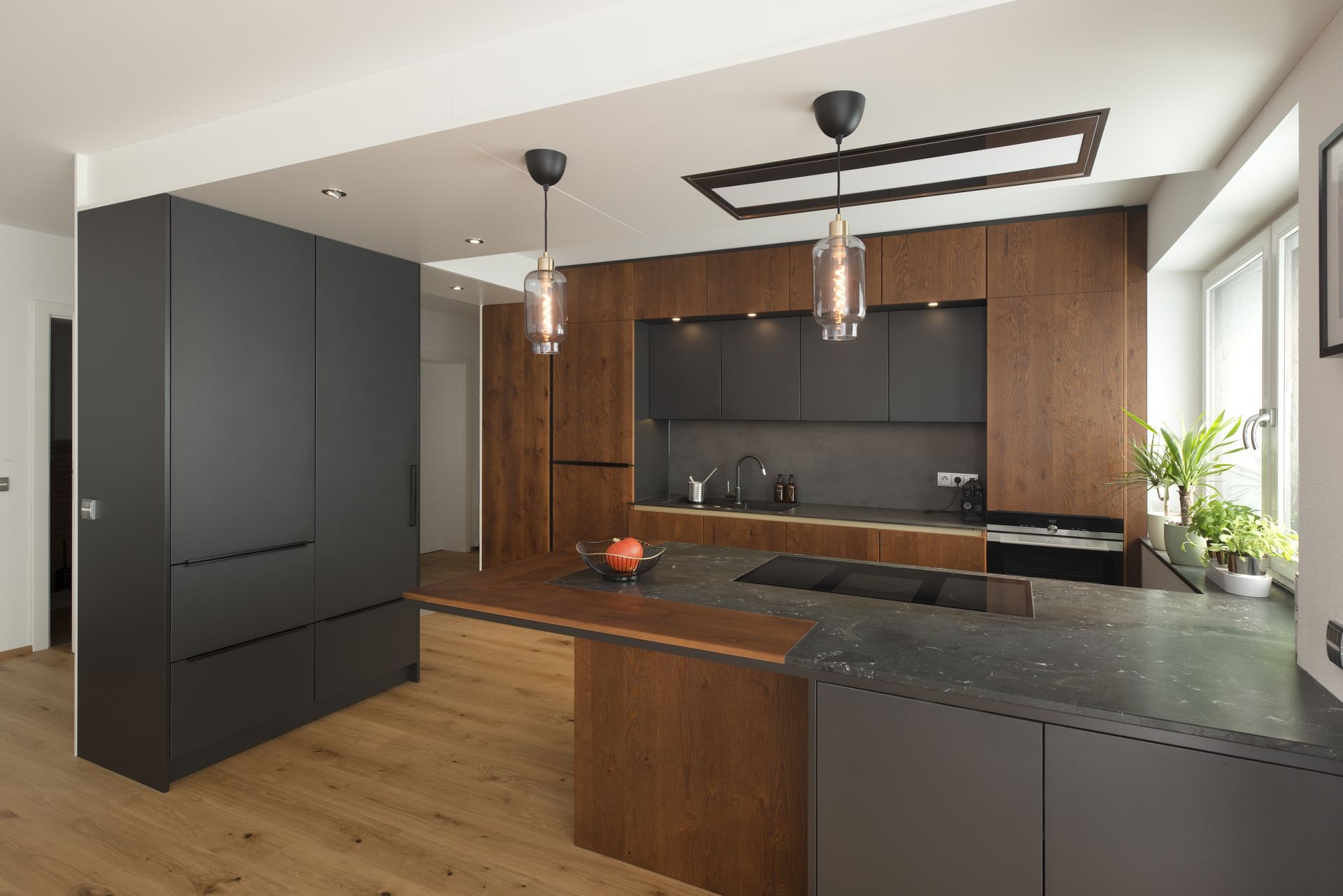 Moderne Küchenkombination mit dunklen Fronten und Kücheninsle.