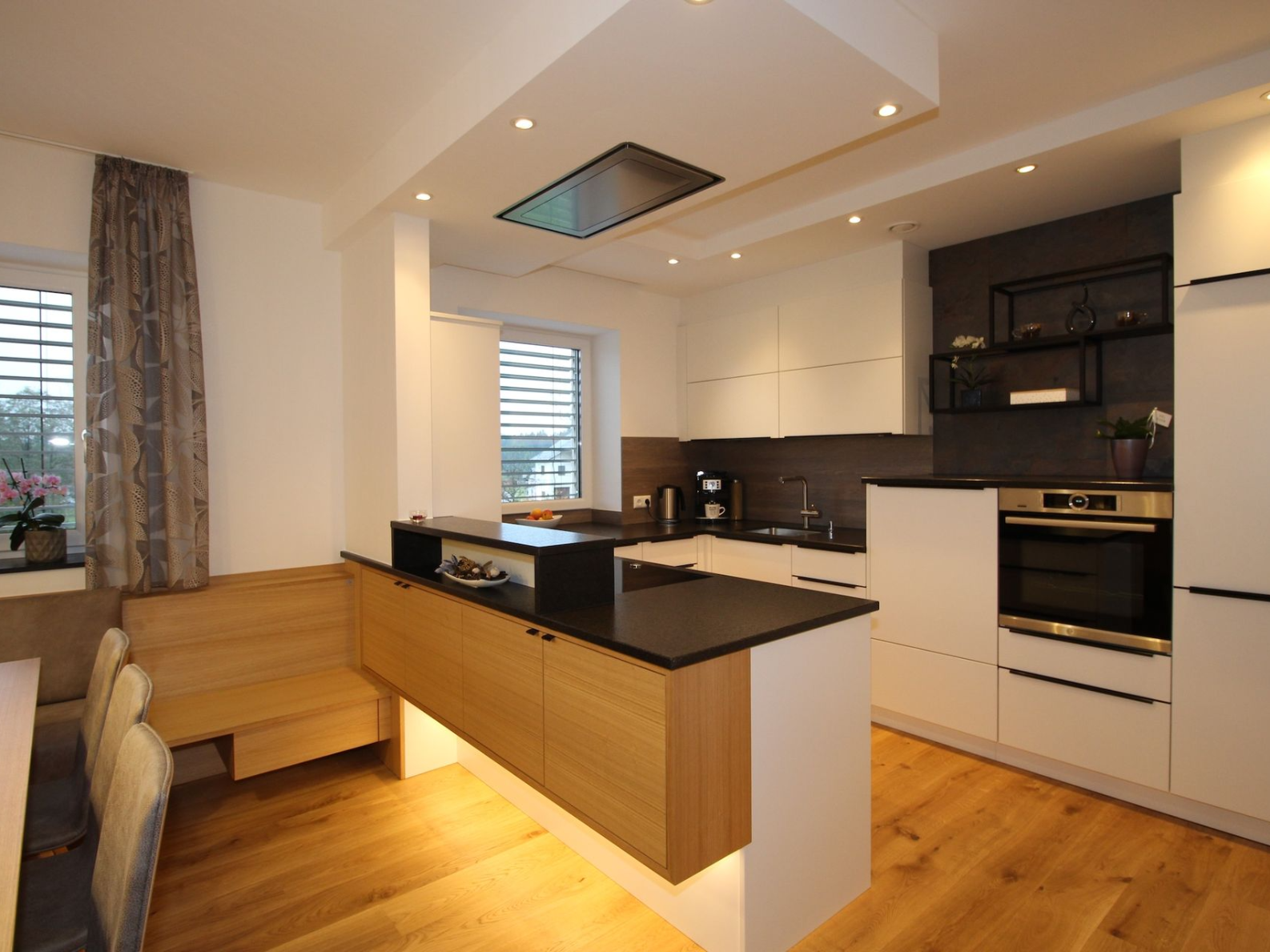 Helle Küche mit dunkler Arbeitsfläche und Holzakzenten