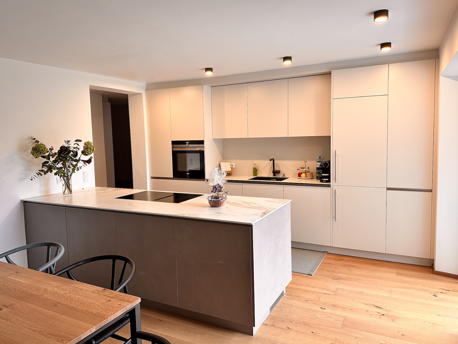 Minimalistische weiße Küchenzeile mit Holzelementen.