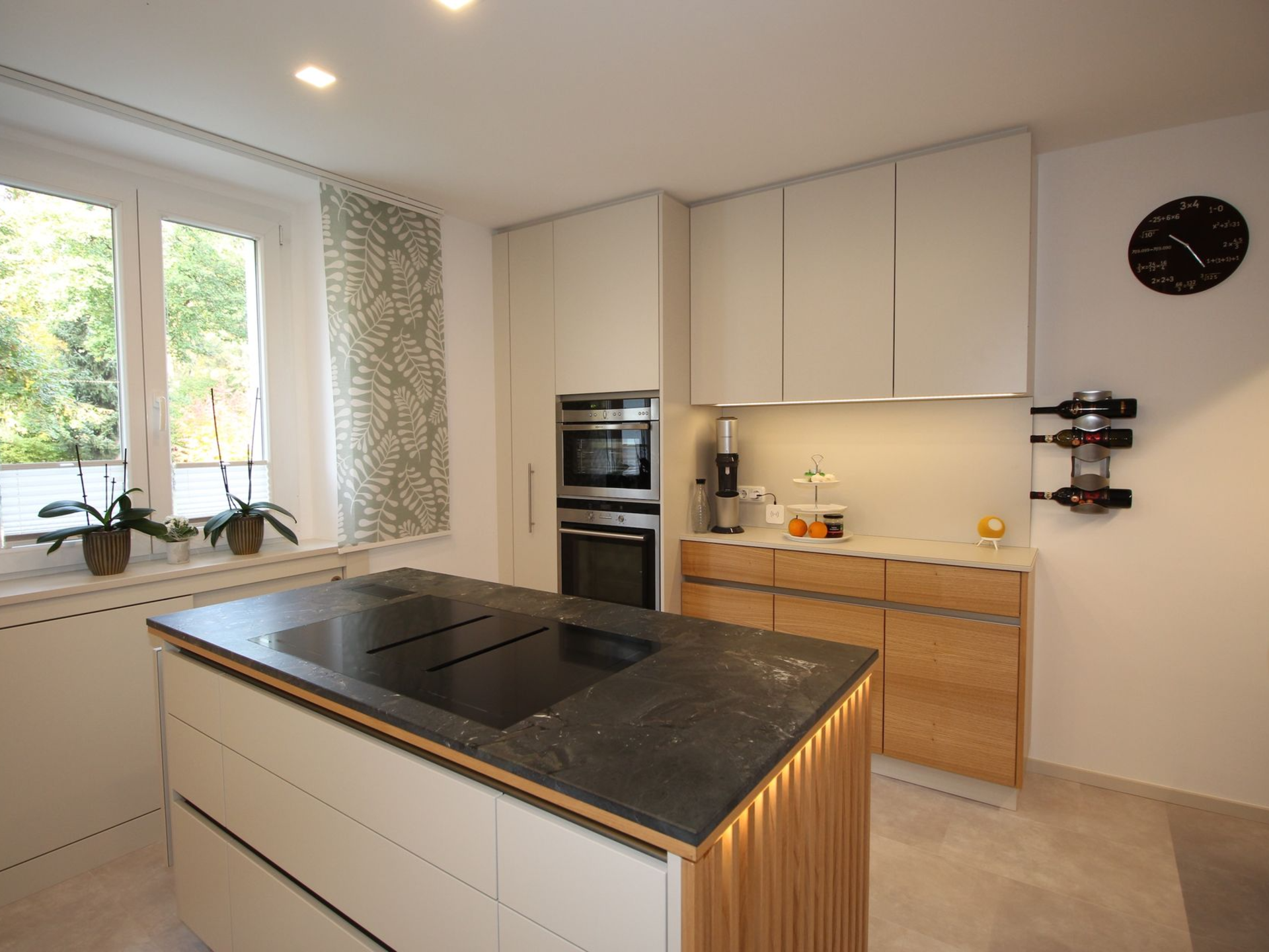 Helle Küche mit dunkler Arbeitsfläche und Holzakzenten