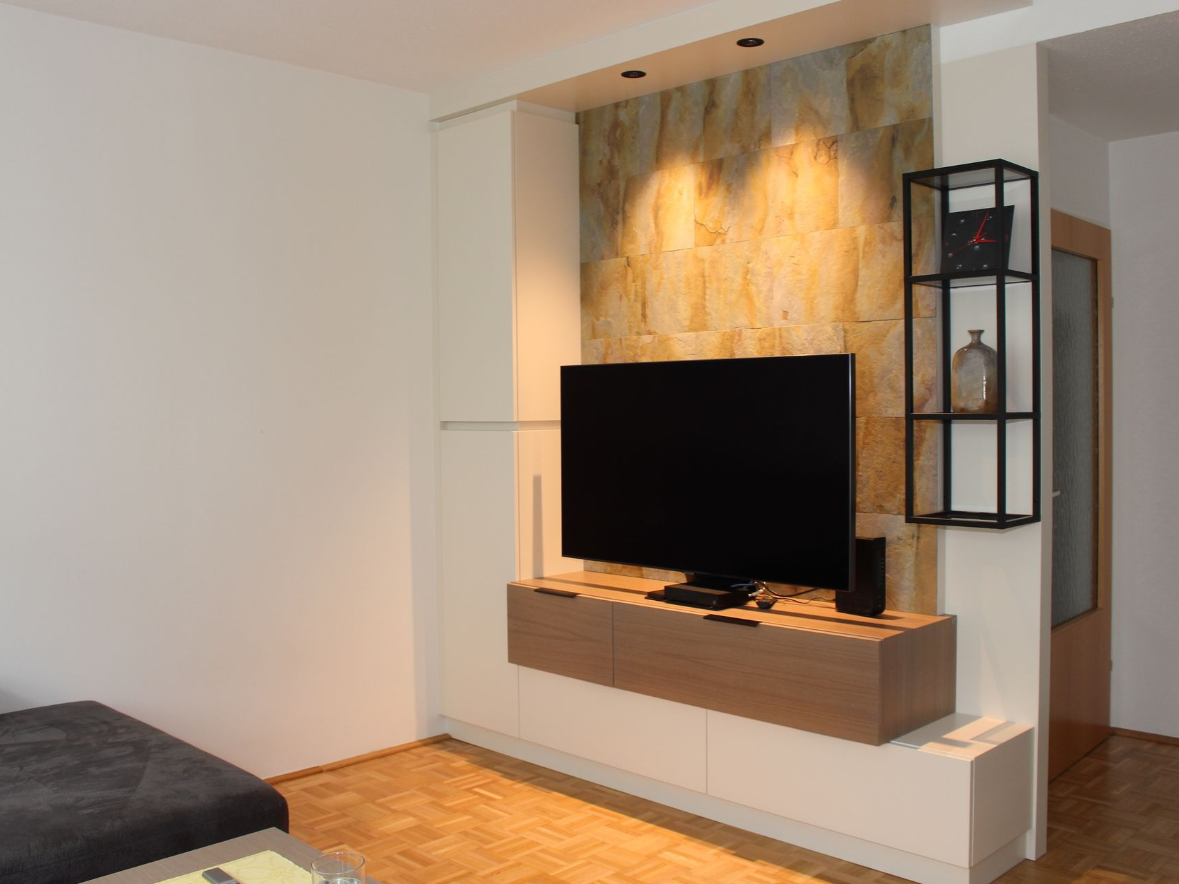 Beleuchtete Wohnwand mit dunklen Akzenten.
